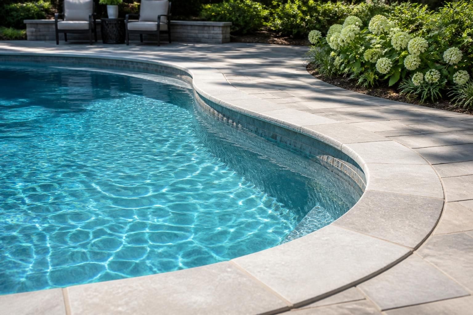 Finished custom inground pool with stone coping and clear water.